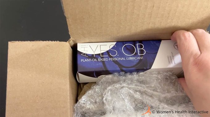 aerial photograph of hand pulling out box of ah yes ob oil-based lubricant after placing an order from their website