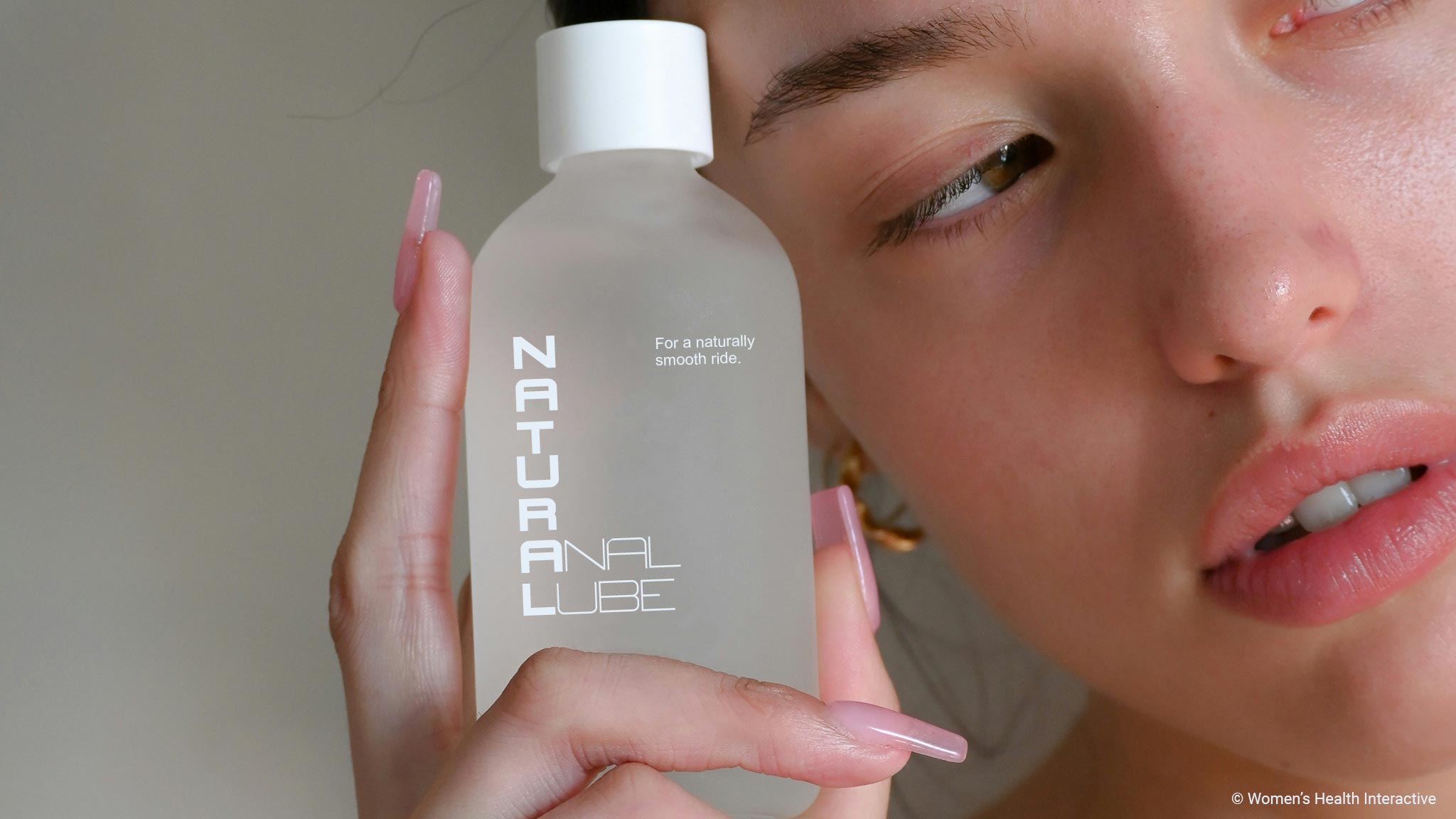 woman holding a bottle with a label that reads natural anal lube