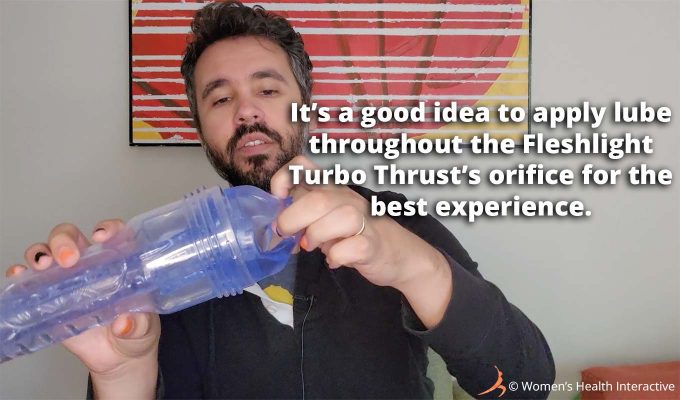 photograph of product tester justin pushing his fingers through the clear transparent fleshlight turbo thrust orifice with text overlay that reads: it's a good idea to apply lube throughout the fleshlight turbo thrust orifice for the best experience