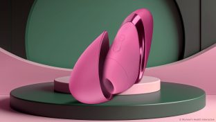 pink womanizer next liberty with the cap slid off to the side and laying on a stage-like platform