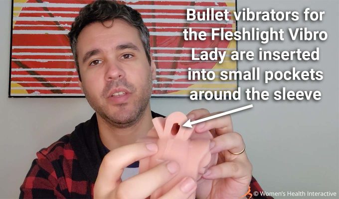 photograph of product tester justin holding the fleshlight vibro lady sleeve in his hand with text overlay that reads bullet vibrators for the fleshlight vibro lady are inserted into small pockets around the sleeve, with an arrow pointing to one