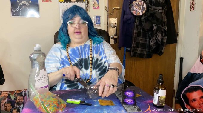 photograph of wednesday cutting the bottom off of the bottle being used to make her diy fleshlight