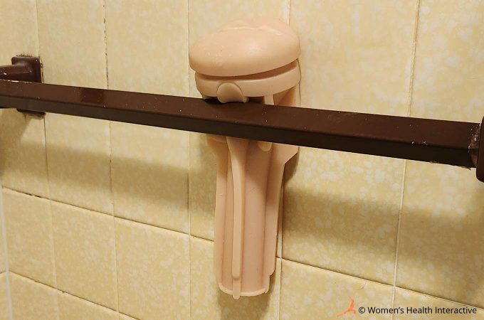 photograph of a fleshlight sleeve hanging from a towel rack along a bathroom wall