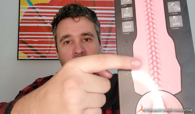 photograph of product tester justin holding the fleshlight vibro lady box in one hand while pointing to the simple finger nub texture map on the back of the box