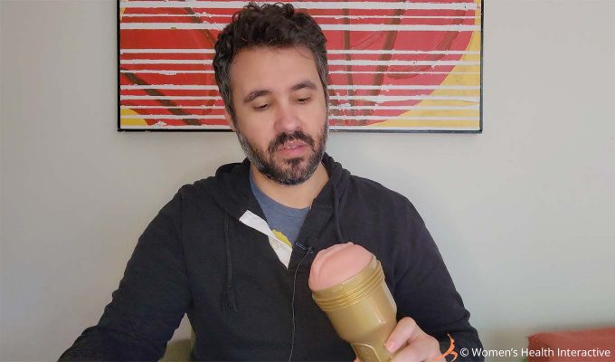 photograph of product tester justin looking at a fleshlight stamina training unit model in his hand, admiring the gold case that surrounds the superskin sleeve