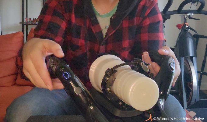 close up photograph of product tester justin holding the fleshlight universal launch automatic masturbator similarly to how he would while using it with hs hands on the handles and his thumbs near the button controls for stroke and speed