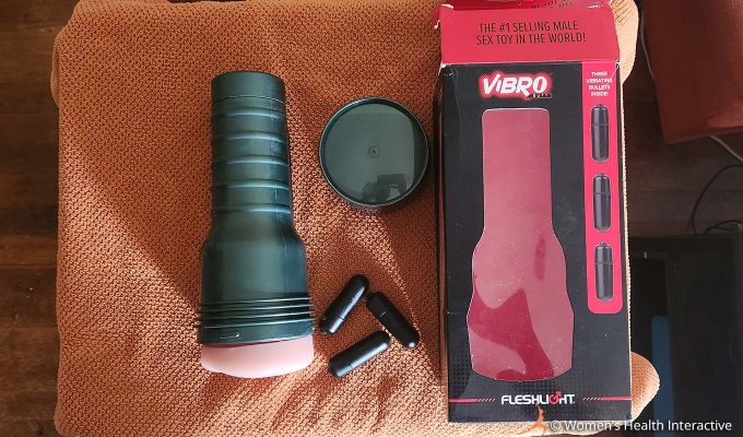 aerial photograph of the fleshlight vibro butt with its three bullet vibrators, cap, and box on a fabric-covered surface