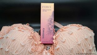 foria awaken arousal oil with cbd box nestled between the cups of a lacy bra