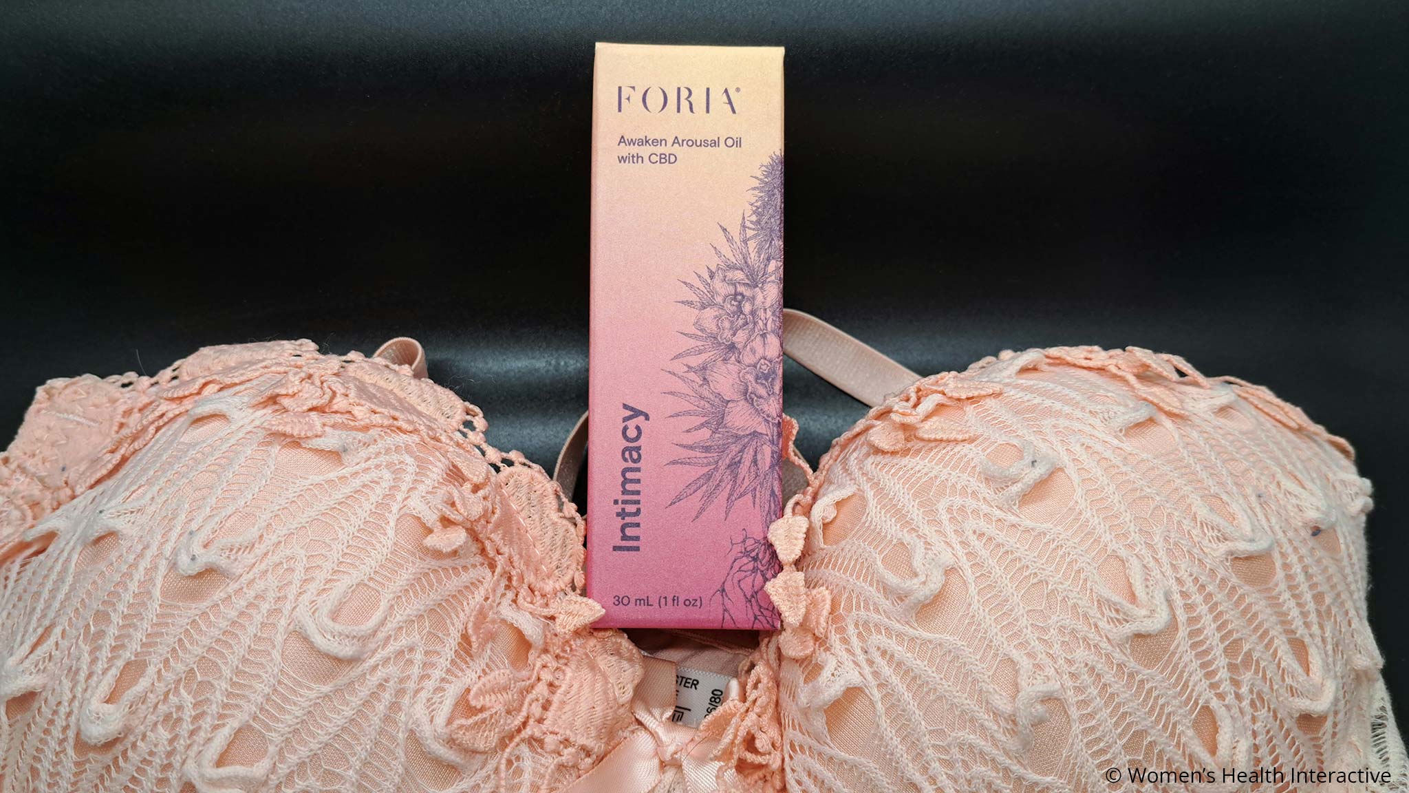 foria awaken arousal oil with cbd box nestled between the cups of a lacy bra