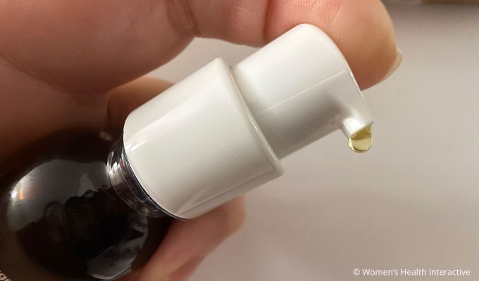 closeup of a single drop of oil from the foria awaken arousal oil bottle pump to show what it looks like, pale yellow drop