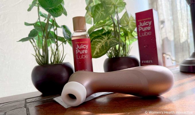 satisfyer pro 2 clit sucking vibrator and condoms with juicy pure lube in the background to show the lube's compatibility with all condoms and sex toys
