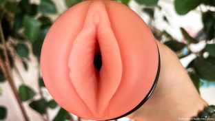 closeup photograph of a hand holding a fleshlight with the vulva facing the viewer, the surface of the material completely pristine and clean with no evidence of mold or mildew
