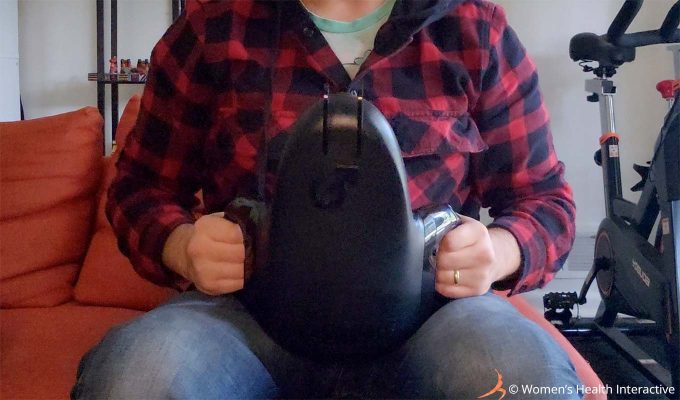 closeup photograph of product tester justin holding the fleshlight universal launch automatic masturbator over his pelvis to demonstrate its use while sitting upright on a couch