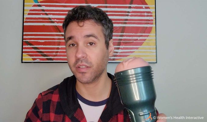 photograph of product tester justin holding the fleshlight vibro lady in one hand while making a slightly surprised expression on his face at the intensity of the male sex toy and stroker