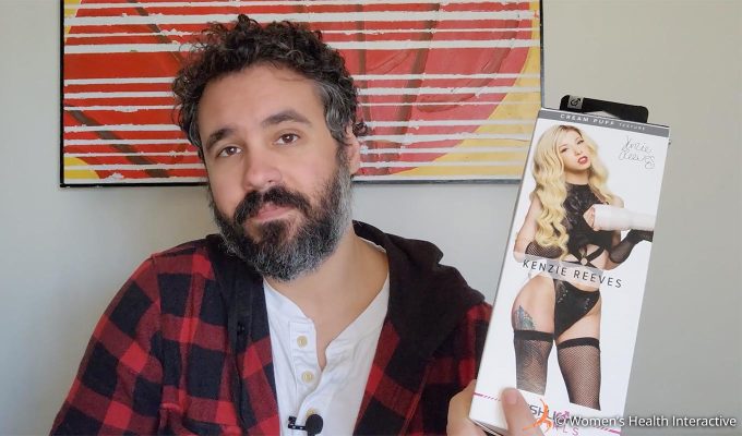photograph of product tester justin holding the kenzie reeves fleshlight box in his hand to display the model's photograph on the cover with an indifferent expression on his face because her body is not his type, but she is still among the most noteworthy tight and intense sleeve textures
