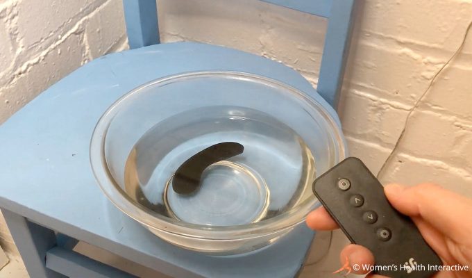 photograph of the satisfyer little secret panty wearable vibrator being tested in a bowl of water while operated via its remote control
