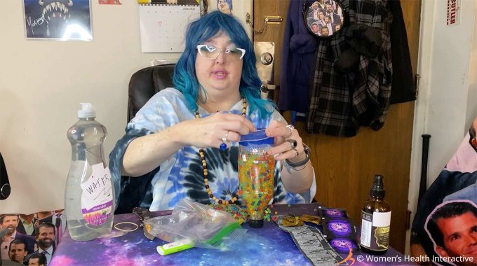 photograph of wednesday pulling the opening of the condom over the edges of the bottle she's using for her diy fleshlight
