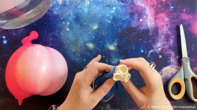 photograph of hands holding deflated balloons, three small ones tucked inside a larger one