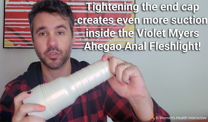 photograph of product tester justin holding the violet myers fleshlight in his hands while demonstrating how the end cap turns with text overlay that reads: tightening the end cap creates even more suction inside the violet myers ahegao anal fleshlight