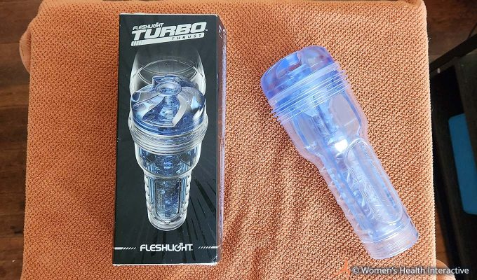 aerial photograph of the clear transparent fleshlight turbo thrust with its box on a cloth-covered table