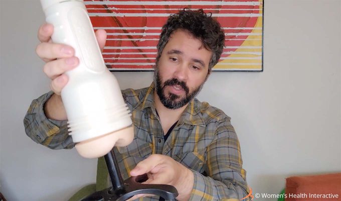 photograph of product tester justin demonstrating how to put a fleshlight on the warmer by sliding the warming stick into the orifice of the pocket pussy sleeve
