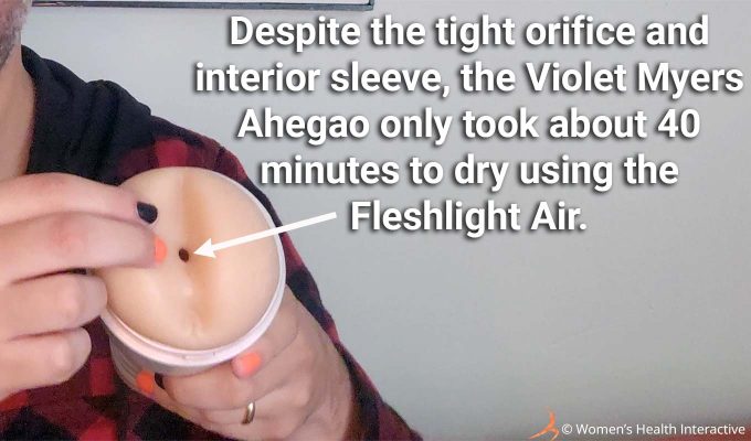 close up photograph of product tester justin holding the anal violet myers fleshlight with his finger pointing toward the orifice with text overlay that reads: despite the tight orifice and interior sleeve, the violet myers ahegao only took about 40 minutes to dry using the fleshlight air