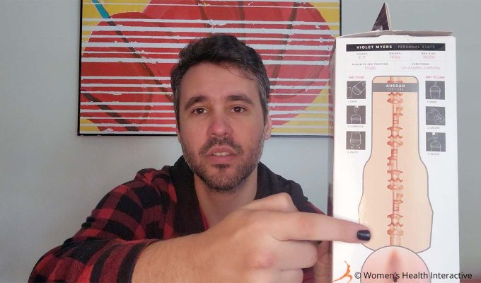 photograph of product tester justin holding the violet myers ahegao anal fleshlight box in his hand while pointing to the key lock-like texture on the back of the box to display what it looks like to the viewer