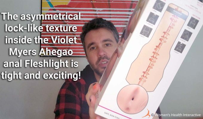 photograph of product tester justin holding the violet myers anal fleshlight box in his hand to display the internal texture map on the back with text overlay that read: the asymmetrical lock-like texture inside the violet myers ahegao anal fleshlight is tight and exciting