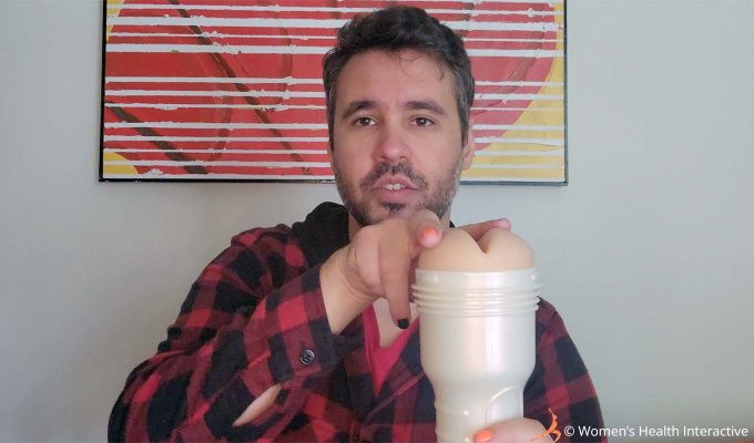 photograph of product tester justin holding the violet myers fleshlight with anal ahegao texture while pressing his fingers into the fleshy area around the anal orifice to demonstrate its cushioning