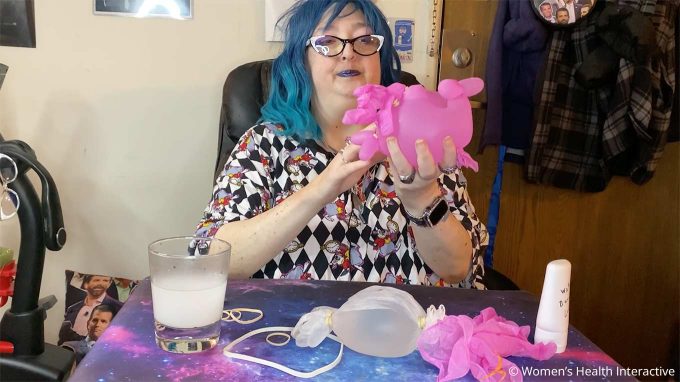 photograph of wednesday looking at her glove fleshlight with an expression of uncertainty