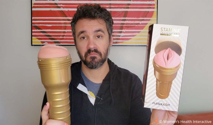 photograph of product tester justin holding the fleshlight stamina training lady pocket pussy in one hand and its box in the other while making a playfully curious frowny face