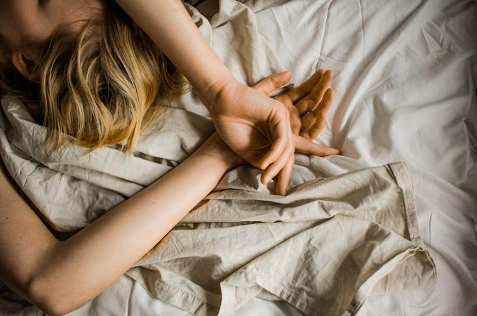 aerial view of woman's hands and arms as she lays in bed